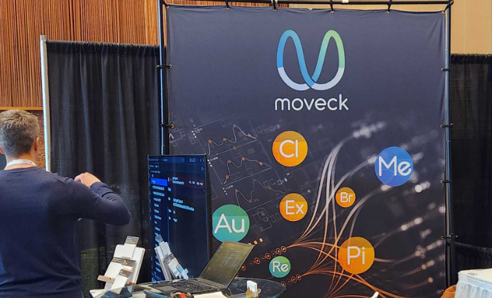 The Moveck stand at the WCB 2026 congress in Vancouver, with the brand backdrop showing the application marks, a laptop and a workstation on the table